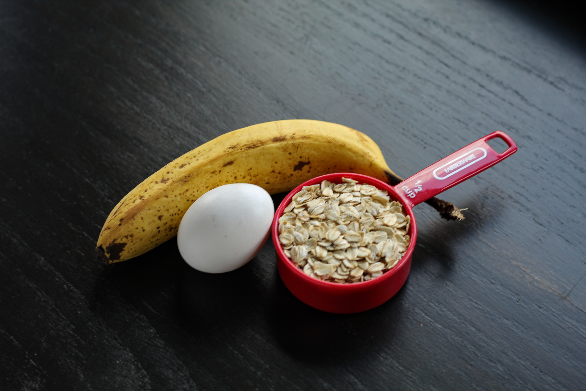 Banana, egg, and oatmeal sitting on a cutting board.