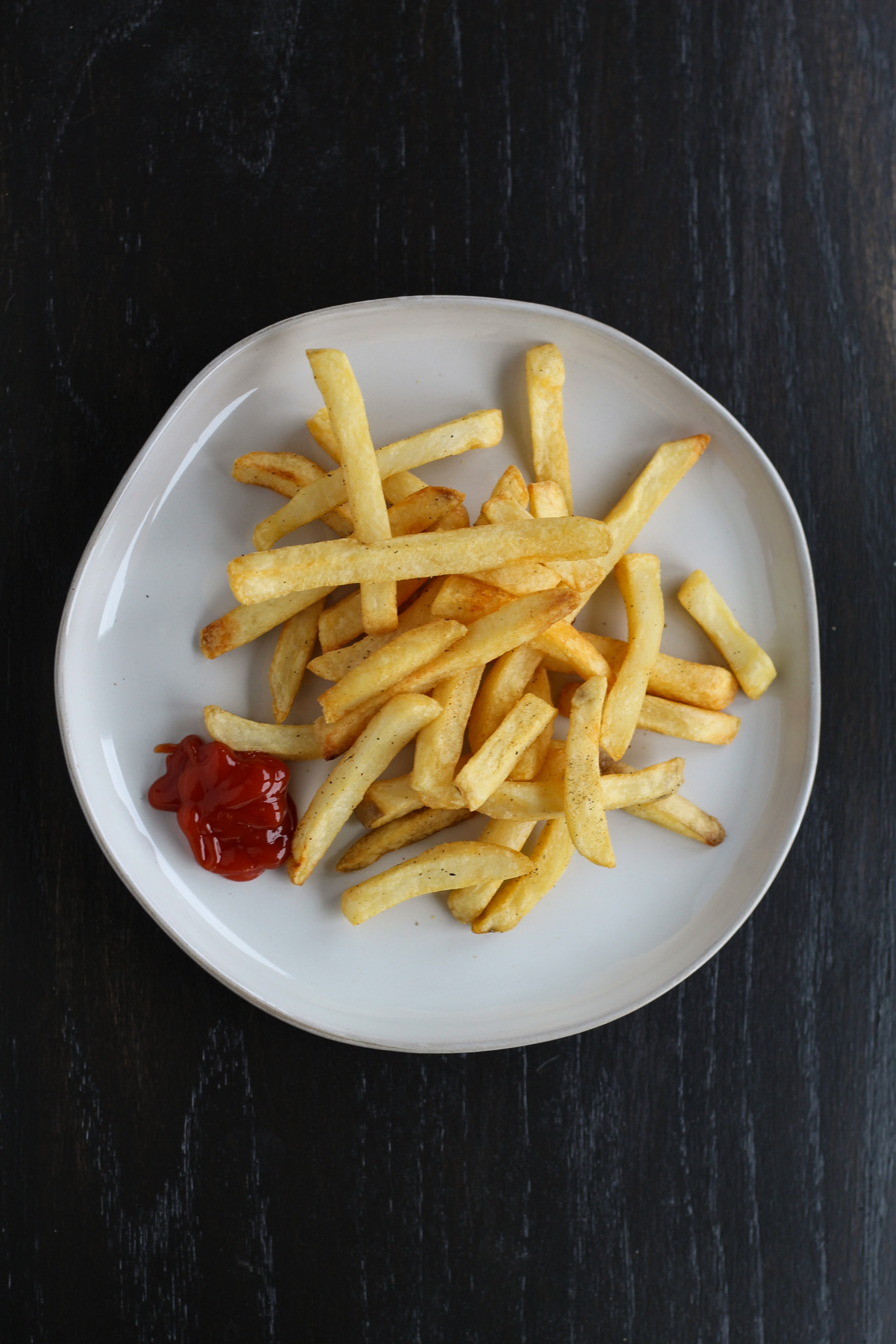 french fries on plate next to ketchup