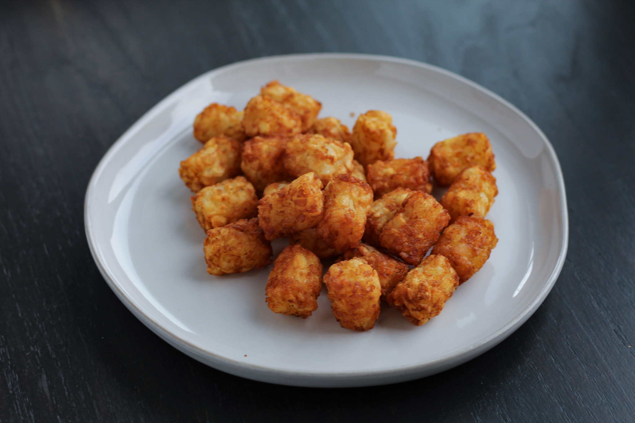 frozen tater tots on a plate after being cooked in an air fryer