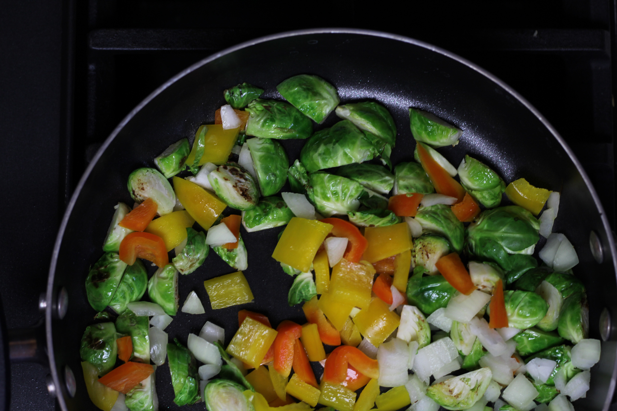 brussels sprouts, onions, and peppers, sautéing in pan