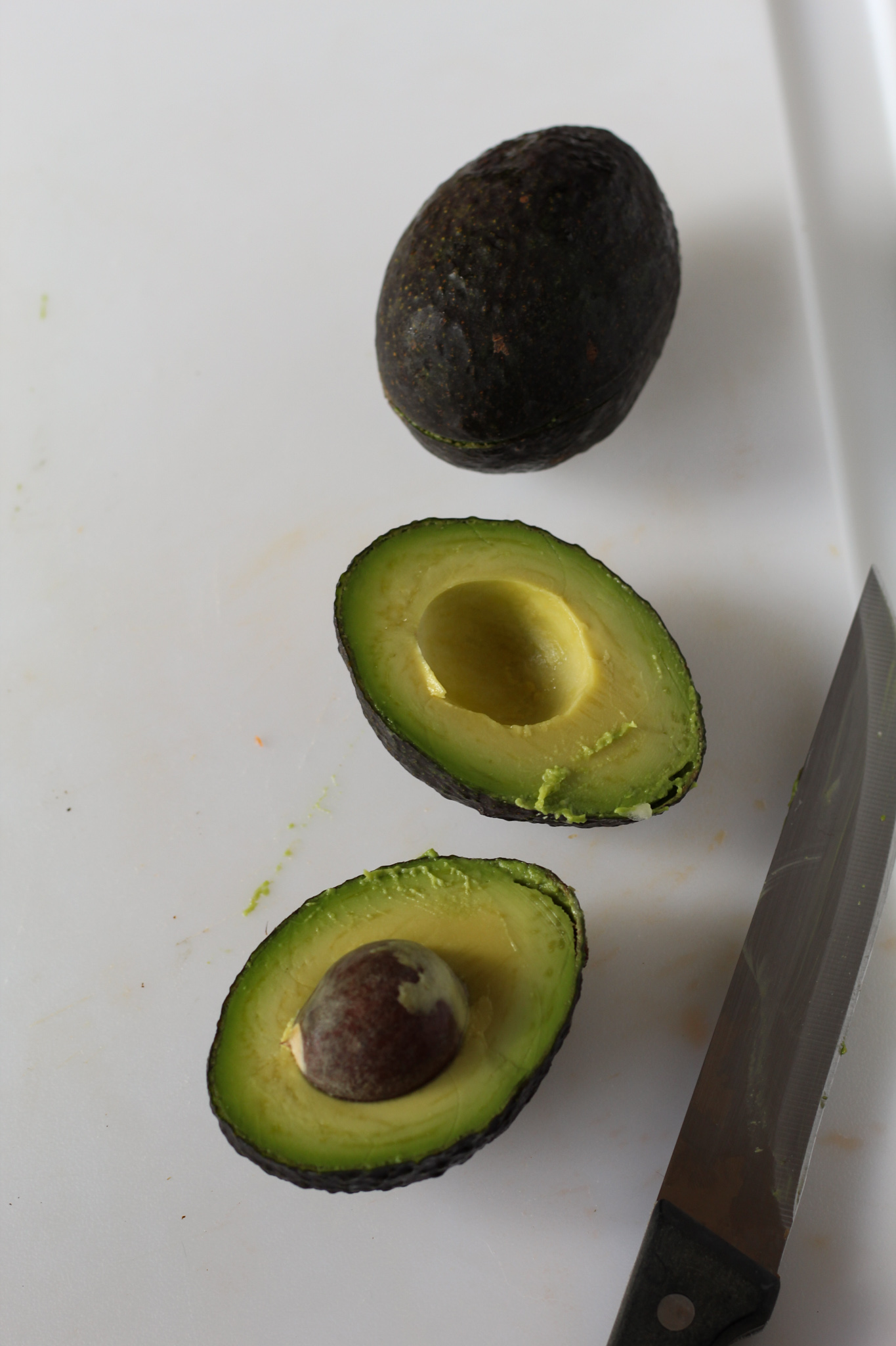 avocado cut in half on cutting board