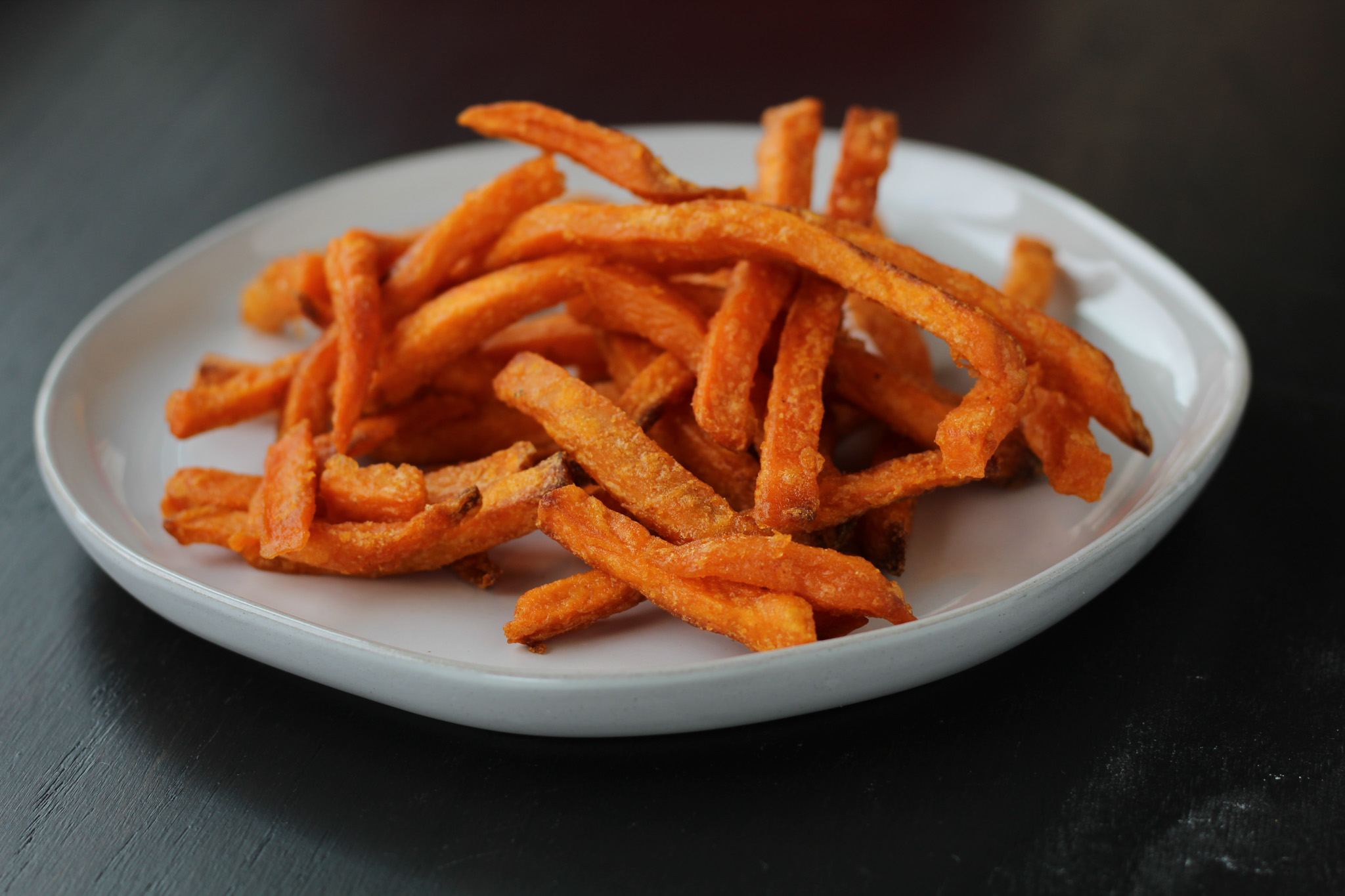 Frozen sweet potato fries on a plate after being cooked in an air fryer